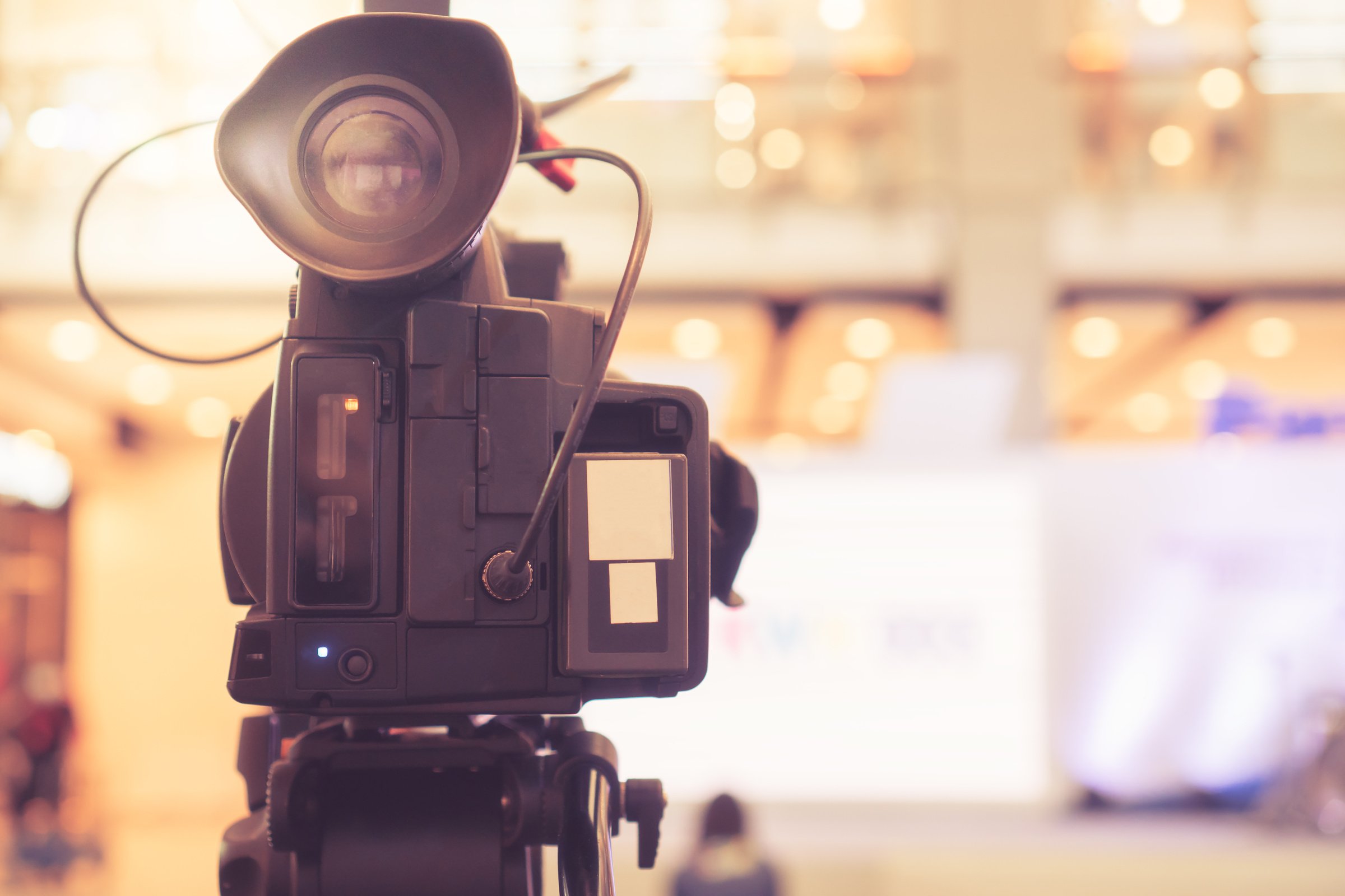 Blurred of Video camera recording film shooting of grand opening in conference hall Live streming wifi microphone sending for presentation with bokeh light background. Media Production Process Concept